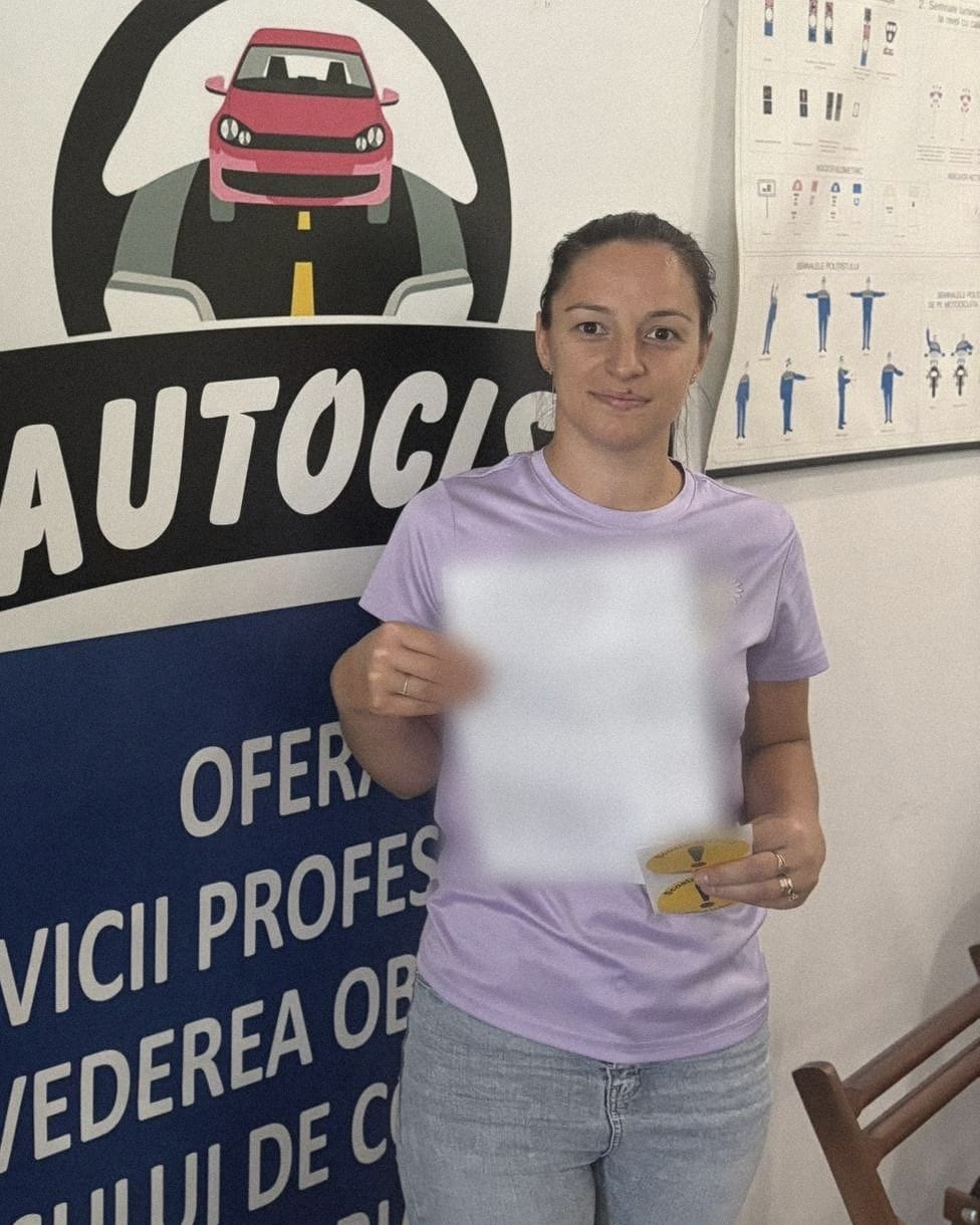 Absolventă a Școlii de șoferi Autocis cu actele de la examen și semnele de începător, în fața bannerului Școlii de șoferi Autocis din sediu