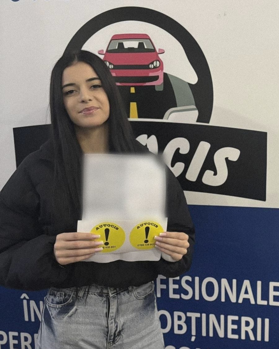 Absolventă a Școlii de șoferi Autocis cu actele de la examen și semnele de începător, în fața bannerului școlii, sub mașina din siglă