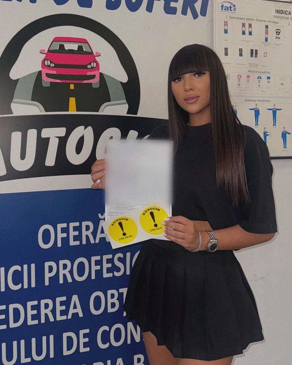 Absolventă a Școlii de șoferi Autocis cu actele de la examen și semnele de începător, în fața bannerului Școlii de șoferi Autocis